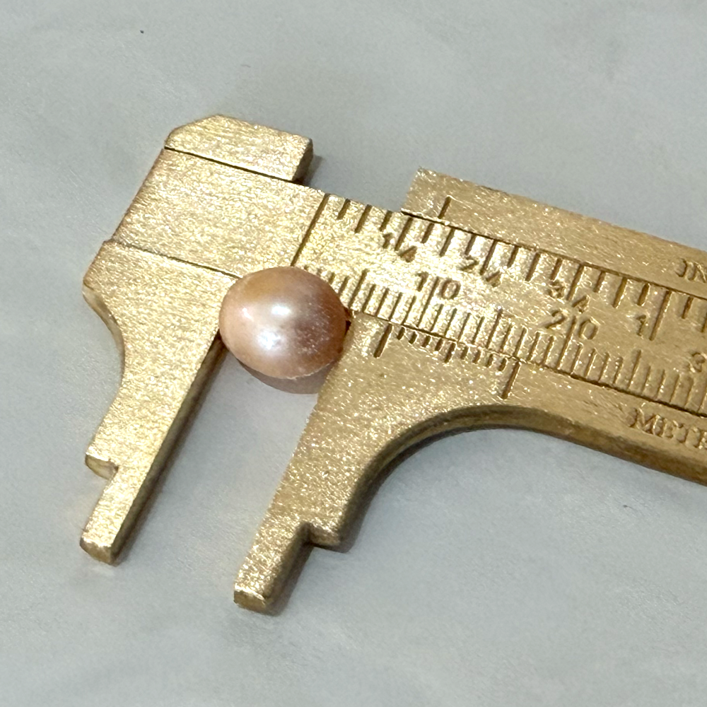 A pearl being measured and polished